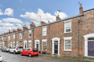 a row of brick buildings with cars parked in front at The Little Domus - modern YORK home with HOT TUB in York