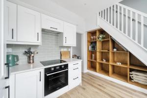 a kitchen with white cabinets and a staircase at The Little Domus - modern YORK home with HOT TUB in York