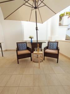 a patio with two chairs and a table with an umbrella at L'Archetto romantic suite in the center of Anacapri in Anacapri
