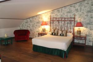 a bedroom with a bed and a red chair at Palacete de la Ochava in Valdilecha