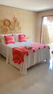 a bedroom with a large bed with red pillows at Chalés Milagres Beach in São Miguel dos Milagres