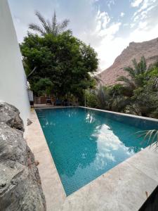 a swimming pool with a mountain in the background at Nomad inn Tiwi in Ḩillat al Ḩişn