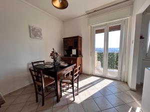 d'une salle à manger avec une table, des chaises et une fenêtre. dans l'établissement Appartamento con vista mare e parcheggio, à Trieste