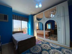 1 dormitorio con paredes azules, 1 cama y espejo en GEM & Pyramids Entire Apartment, en El Cairo