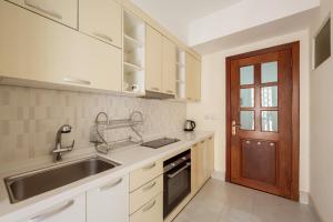 a kitchen with white cabinets and a sink and a door at E&V Apartment in Phnom Penh