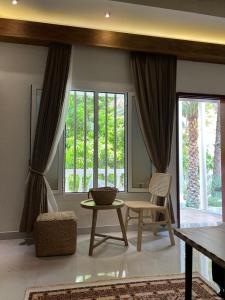 sala de estar con mesa, sillas y ventana en Nomad inn Tiwi, en Ḩillat al Ḩişn