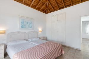 a white bedroom with a bed with a striped blanket at La Villa La Palma- 1 dormitorio B in Los Barros +18 photos