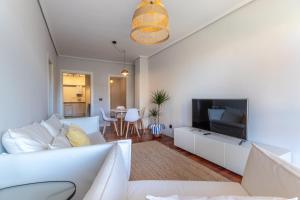 un salon avec un canapé blanc et une télévision dans l'établissement Bakio Beach XVI by Aston Rentals, à Bakio