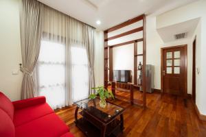 E&V Apartment في بنوم بنه: غرفة معيشة مع أريكة حمراء وطاولة