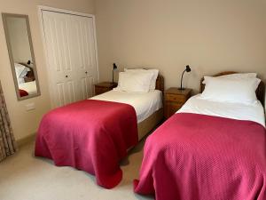 Aleberry Bed and Breakfast في لويس: غرفة نوم بسريرين ذات أغطية وردية وبيضاء