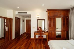um quarto com uma secretária, uma cama e um espelho em E&V Apartment em Phnom Penh