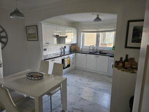 a kitchen with white cabinets and a table with chairs at Snug - Colquhoun Square Apartment in Helensburgh