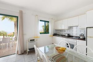 a kitchen with white cabinets and a glass table at Villa Verde Superior B in Los Barros