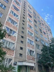 un grand bâtiment avec des motifs rouges et blancs dans l'établissement Asaapart Orbita 2, à Almaty