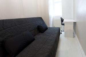 - un canapé noir dans le salon avec une table dans l'établissement L'Hibiscus Rouge, à Brest