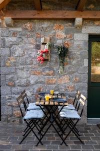 een tafel en stoelen voor een stenen muur bij 9b-The Tiny House in Sežana