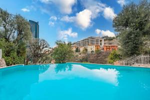 una piscina blu con un edificio sullo sfondo di Monaco Border, sea view, Parking a Beausoleil