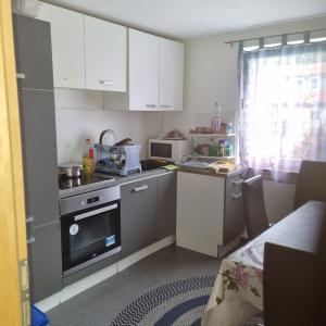 a small kitchen with white cabinets and a stove at Pension Haus am Malesfelsen in Albstadt