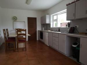 a kitchen with white cabinets and a table and a chair at Tranquil Country Escape West Coast Adventure Awaits in Galway