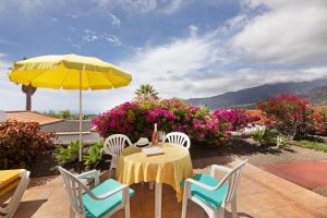 Los BarrosにあるLa Villa La Palma- 2 dormitorios Bの黄色い傘と花のテーブルと椅子