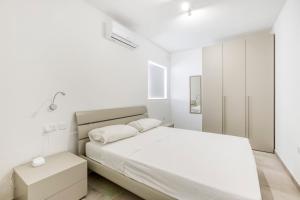 a white bedroom with a large bed and a cabinet at GZIRA Suite 14-Hosted by Sweetstay in Il-Gżira