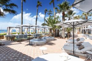 a patio at the beach with chairs and umbrellas at Don Carlos Resort & Spa in Marbella