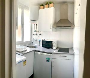 a white kitchen with a sink and a microwave at Alcalá zona Centro in Alcalá la Real