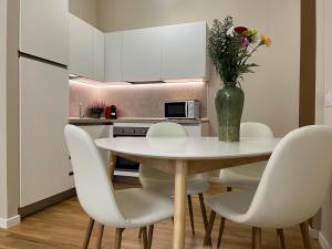 une table de salle à manger avec des chaises blanches et un vase avec des fleurs dans l'établissement REGINA by The Blue Twins apartments Milano, à Milan