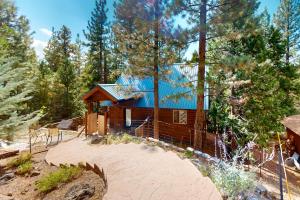 a wooden cabin with a blue roof in the woods at Fawn Voyage in Portola