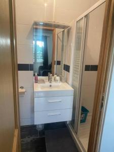 een badkamer met een witte wastafel en een spiegel bij L8 - Villiers-le-Bel proche ROISSY & PARIS in Villiers-le-Bel