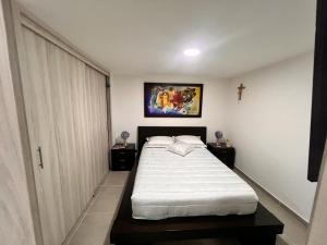 ein Schlafzimmer mit einem Bett und einem Kreuz an der Wand in der Unterkunft AlOJAMIENTO EN BELLO in Bello