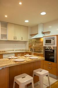 a kitchen with two white stools and a counter top at Charming 2 Bedroom Apartment at Sevilla City Center By Cityzen in Seville