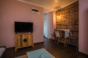 a living room with a flat screen tv and a brick wall at Athina's little apartment in Thessaloniki