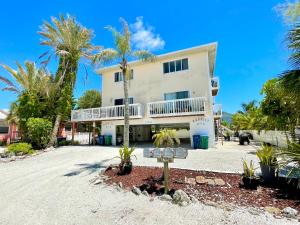a white house with palm trees in front of it at Two story condo with ocean on one side and bay on other only steps away in Bradenton Beach