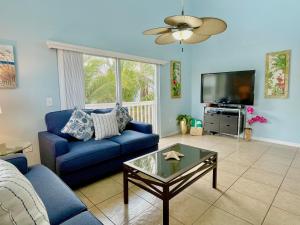 a living room with a blue couch and a tv at Two story condo with ocean on one side and bay on other only steps away in Bradenton Beach