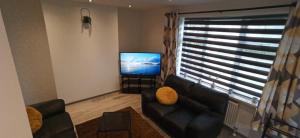 een woonkamer met een bank en een flatscreen-tv bij Broxtowe house -3 bed House parking Nottingham in Nottingham