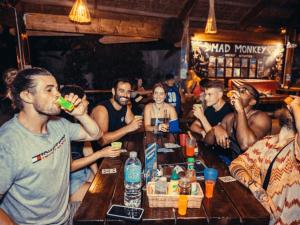 een groep mensen aan een tafel in een bar bij Mad Monkey Hostel Siargao in General Luna