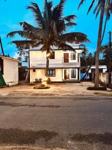 a house with a palm tree in front of it at ENOCEAN HOMESTAY in Cherai Beach +45 photos