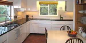 a kitchen with white cabinets and a table with a bowl of fruit at Vipers Quay in Dartmouth