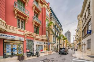 una strada con un edificio rosa su una strada cittadina di Monaco border- 5mn Place du Casino- Hypercenter a Beausoleil