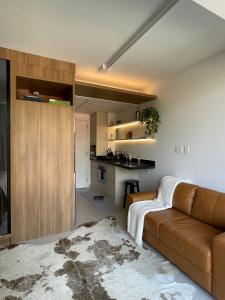 a living room with a brown couch and a kitchen at Vossa bossa Vila Madalena in Sao Paulo