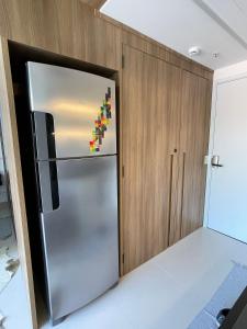 a stainless steel refrigerator in a kitchen with wooden cabinets at Vossa bossa Vila Madalena in Sao Paulo