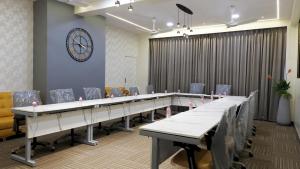 una mesa larga con sillas y un reloj en la pared en Hotel Sai Miracle, en Shirdi