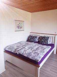 Eppenschlag的住宿－Haus-Daxberg-idyllisch-gelegen-im-Bayerischen-Wald-Ferienwohnung-mit-Zimmer-Kueche-Bad，一间卧室配有一张带紫色棉被的床