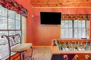 uma sala de estar com uma mesa e uma televisão na parede em Cozy Cub Cabin em Gatlinburg