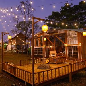 ein Holzhaus mit Lichtern und einer Gitarre auf einer Terrasse in der Unterkunft Rumhaoy Maison in Phumĭ Pu Pal