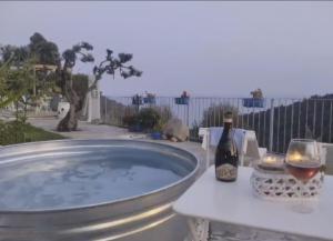 a hot tub with a bottle of wine and a glass at Message in a Bottle Bed and Breakfast in Camporosso