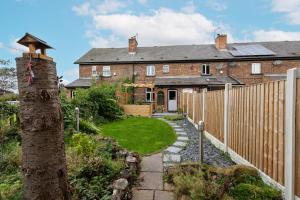 a brick house with a fence and a yard at Wakefield Canal Cottage - Parking, Self Check-in, Fast WiFi, Large Garden, Canal Side Views - Contractors, Families, Long Stays in Wakefield