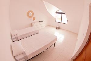 a white bedroom with two beds and a window at Villa PalMarina in Praia