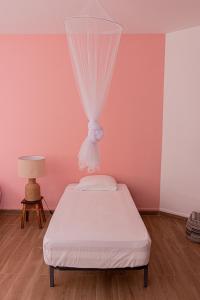 Bett in einem Zimmer mit einer rosa Wand in der Unterkunft Villa PalMarina in Praia